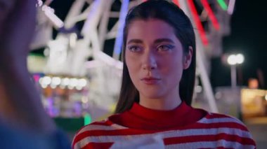 Renkli dönme dolapta konuşan kız arkadaş konuşuyor. Olumlu kadın kız arkadaşıyla hafta sonu sohbetinin tadını çıkarıyor. Gülen genç lunaparkta elinde patlamış mısırla gülüyor.