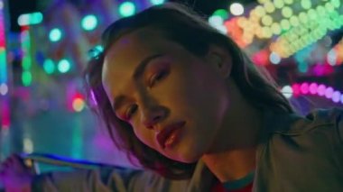 Neon Funfair atlıkarınca pozu veren çekici bir kadın. Muhteşem modaya uygun model. Haftasonu, aydınlık eğlence parkında dinleniyor. Tatil randevusundaki romantik kız. Şenlikli moda kadını