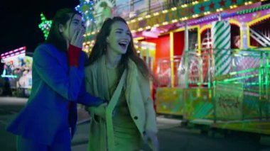 Mutlu arkadaşlar eğlence parkında eğleniyor. Neşeli kızlar atlıkarınca caddesinde gülüyor. Neşeli kız kardeşler hafta sonu şehir festivalinde birlikte eğleniyorlar. Tatil eğlencesi konsepti