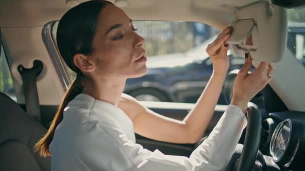ブルネットは フロントシートの近くに座っている車の鏡を見ています 高価な自動車の中で自信を持ってカメラを見ているポッシュスタイリッシュな女性 Vip車にポーズする豪華なビジネスマンドライバー シックビジネス — ストック動画
