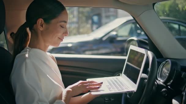 聪明的女老板坐在前排靠拢的座位上 目光炯炯地坐在电脑屏幕上 自信的女商人在豪华汽车内的计算机上远程工作 在笔记本上微笑的女士上网 — 图库视频影像