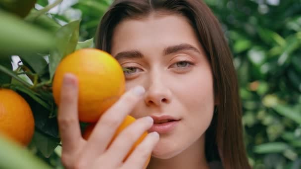 여자는 초상화에서 오렌지 과일에 식물원에서 카메라를 자신감 화려한 소녀가 닫습니다 — 비디오