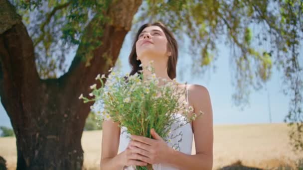 자연에서 부드러운 여자의 초상화 햇빛에 신선한 카모마일 꽃다발과 가까운 즐기는 — 비디오