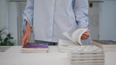 Kadın elleri yakın planda kitap seçiyor. Kitapçı ziyaretçisi, modern mağazada edebiyat sayfalarını karıştırıyor. Tanınmayan kız hafta sonu alışverişinden zevk alıyor dükkandan ilginç edebiyat seçiyor..