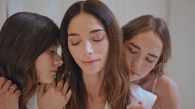 Çekici bir kadın portresi. Kapalı alanda kucaklaşıyor. Birlikte poz vermeyi seven destekleyici bir aile. Gülümseyen kızlar arkadaşlarıyla kucaklaşıp nazik duygular ifade ediyorlar. Çekici mankenler kameraya bakar. Doğal güzellik kadınlığı
