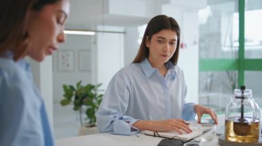 Ofiste çalışan genç bir yardımcı. Takım toplantısına odaklanmış yönetici evrakları kontrol ediyor. Başarılı çalışan şirket stajyerlerinin iş kadınlarına yardım etmeyi öğrenmesi. Profesyonel işbirliği kavramı.