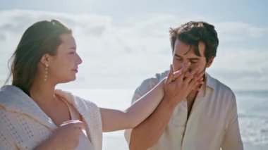 Romantik çift yaz tatilini güzel bir plajda geçiriyorlar. Sevgi dolu adam elini öpüyor güzel karısı güneşli okyanus kıyısında yürüyor. Yaklaş. Yakışıklı koca, sevgili kadına sevgisini ifade ediyor..