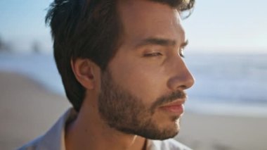 Güzel okyanus kıyısında poz veren seksi sakallı adam kameraya yaklaş. Kumsalda tek başına duran yakışıklı İtalyan maço portresi. Çekici genç adam doğada dinleniyor..