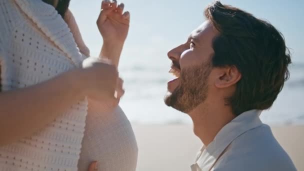 Future Father Caressing Pregnant Belly Sitting Wife Sunny Sea Coast — Stock Video