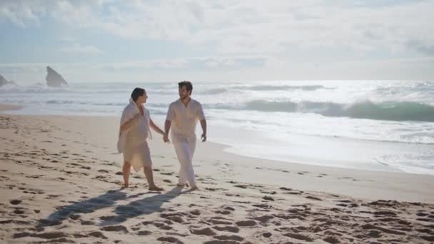 楽しい配偶者は 赤ちゃんを期待して一緒に楽しんで海岸散歩を楽しんでいます 未来の両親は嵐の海の波の近くで砂浜を歩いています 夏の朝 ハッピーケアフリー 妊娠中のカップル ロマンチックな一日を過ごす — ストック動画