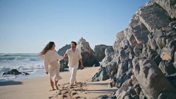 赤ん坊を期待するペアは一緒に笑う海岸散歩を楽しんでいます 砂浜で夫を率いる幸せな笑顔の妊婦 美しい夏の海岸でリラックスする陽気なロマンチックな家族カップル — ストック動画