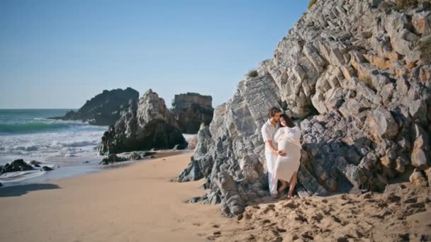 Ніжна Вагітна Пара Позує Кам Янистому Пляжі Спираючись Грубі Камені — стокове відео