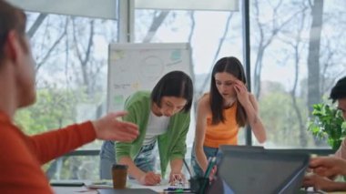 Şirket ofisinde yaratıcı girişimciler beyin fırtınası yapıyor. Asyalı kadın, çalışma masasında oturan erkek arkadaşa evrakları gösteriyor. Çeşitli iş arkadaşları projeyi tartışıyor. Genç tasarımcılar birlikte çalışıyor. 