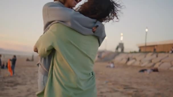 兴奋的恋人拥抱在海洋日落海滩特写 金发男友在海景处扭动着他可爱的女朋友 一个非常快乐的女人在海滨与男人欢欢喜喜 幸福的概念 — 图库视频影像