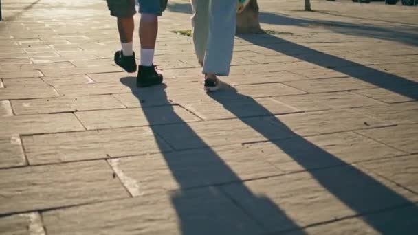 在市区的人行道上 一双便鞋穿过铺路石 浪漫男人的腿走在柏油路上 不认识的女孩情侣喜欢一起散步 一起铺石头 城市生活方式概念 — 图库视频影像