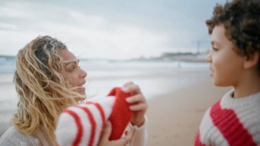 Anne babası küçük oğluna sıcak bir şapka takmış. Genç ve güzel anne, sonbaharda deniz kenarında yürüyen kıvırcık çocuğa bakıyor. Güzel bebek bakıcısı rüzgarlı bir günde örgü örer. Aile hafta sonu konsepti