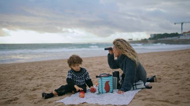 Annesinin oğlu bulutlu sahilde piknik yapıyor. Heyecanlı çocuk sonbahar tatilinde okyanus dalgalarını izlerken rüya görüyor. İyi yolculuklar. Birlikte iyi vakit geçirin. Çocukluk hayal gücü kavramı.