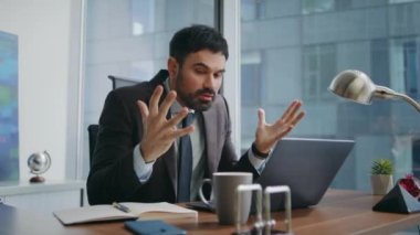 Öfkeli yönetici online toplantıda bağırarak modern işyerini kapatıyor. Sinirli iş adamı dizüstü bilgisayarda bağırıyor kamera tatminsiz video konferansı ofiste. Çılgın patron duygusal hareketler yapıyor.
