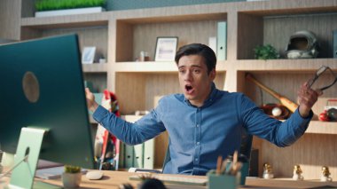 Duygusal iş adamı resmi olmayan ofiste bilgisayar görüntülü arama diye bağırıyor. Yakın plan sinirli yönetici el kol hareketi yaparak görüntülü konuşma yapıyor. Stresli sinirli adam modern işyerinde tartışan yükseltilmiş ses tonuyla konuşuyor.
