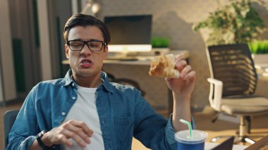 Pizza yiyen iki adam monitör masasında konuşuyor. Esmer serbest çalışanlar rahat iletişimin tadını çıkarıyorlar. Gülümseyen neşeli takım arkadaşları öğle yemeği molasında duygusal konuşuyorlar.