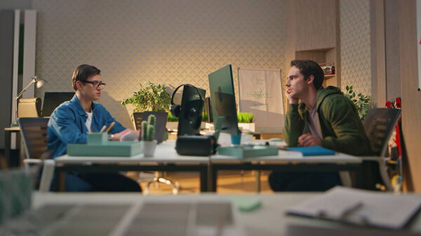 Умные стартаперы общаются в компьютерной комнате. Арт-директор и графический дизайнер обсуждают маркетинговую кампанию для бизнес-партнера. Небольшая творческая команда, работающая в офисе. Два парня консультируют