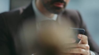 İş adamı elleri iş yerindeki sosyal ağlarda telefon sörfü yapıyor. Gülümseyen iş adamı cep telefonu oturma odasında mesaj okuyor. Mutlu çalışan akıllı telefondaki arkadaşça sohbetin keyfini çıkar.