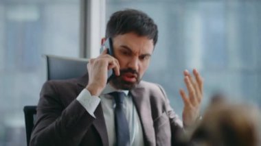 Akıllı telefondan bağıran öfkeli CEO kötü haberlerden rahatsız oluyor. Modern ofiste oturup telefon konuşmalarına bağıran kızgın işadamı. Stresli yönetici hoparlörde tartışıyor..