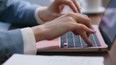 Ofiste dizüstü bilgisayarda klavye yazan kadın elleri yakın çekim yapıyor. Bilgisayarda çalışan bilinmeyen bir iş kadını not defterine not alıyor. Tanımlanamayan işçi ekrandan deftere bilgi yazıyor.