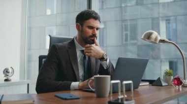 Bilgisayarda çalışan sakallı bir çalışan modern ofiste oturuyor. Düşünceli yönetici lüks işyerinde iş meseleleri arama çözümü düşünüyor. Finans müdürü bilgisayar monitörüne odaklandı.