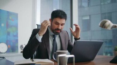 Uzaktan konferansa bağıran öfkeli işadamı ofis çalışma alanını kapatıyor. Duygusal menajer dizüstü bilgisayarlı web kamerasıyla kavga ediyor. Kızgın patron bağırarak iş başarısızlığını işaret ediyor..