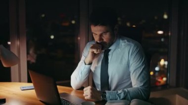 Endişeli ofis müdürü gece geç saatlerde dizüstü bilgisayarda çalışıyor. Kapatın. Sorunlu iş adamı geceleri bilgisayar ekranı yüzünden endişeli görünüyor. Aşırı yüklü şirket çalışanı fazla mesai yapmaktan yoruldu..