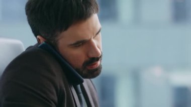 Bilgisayarda yazarken telefonla konuşmakla meşgul. Sakallı şirket yöneticisi, modern ofiste bilgisayardan bilgi almak için müşteriyi arıyor. Aletlerle çalışan kendinden emin bir iş adamı..