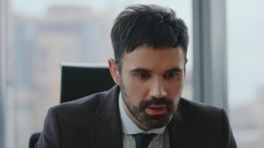 Sinirli girişimci videosu modern işyerinden yakın çekim için arıyor. Şirketteki ortaklarla çevrimiçi görüşme yapmaktan rahatsız olan kızgın iş adamının portresi. Sinirli yönetici sinirli konuşuyor..