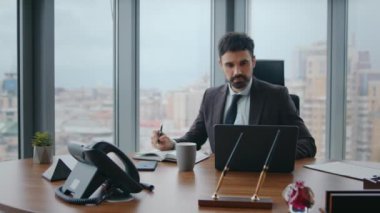 Dalgın yönetici modern dizüstü bilgisayarla çalışırken notlar alıyor. Ciddi sakallı iş adamı ofis masasındaki not defterine fikirler yazmayı düşünüyor. Düşünceli CEO iş stratejisi yaratıyor bilgisayar görünümlü