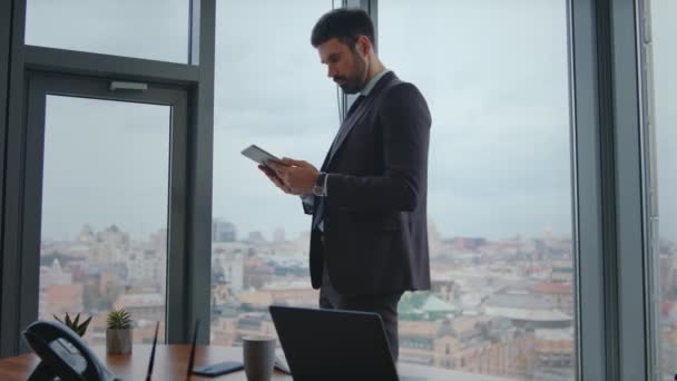 現代オフィスの立っているタブレット スクリーンを見る集中したマネージャー 職場のパッドコンピュータで情報を読む忙しい起業家 インターネットを使用してリモートで働くスマートなひげ付きビジネスマン — ストック動画