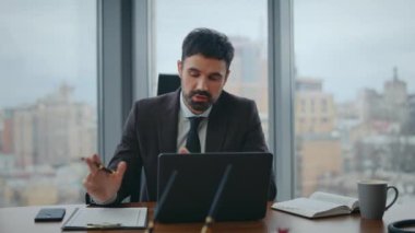 Yönetici videosu lüks ofis masasını kapatıyor. Çevrimiçi konferansta konuşan kendine güvenen sakallı iş adamı dizüstü bilgisayara bakıyor. Şirket web sayfası sırasında not alan ciddi bir işçi..