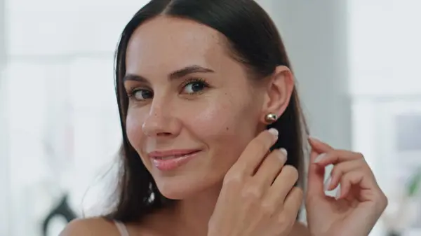 Happy model putting earrings at home pov video. Satisfied woman straightening hair preparing to date at bathroom portrait. Smiling lady enjoy jewellery looking camera close up. Morning routine concept