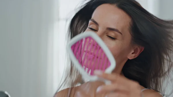 Smiling woman styling hair using hairdryer in bath pov video. Brunette groomed lady drying chevelure at morning home portrait. Satisfied girl looking camera holding hairstyling device at house closeup