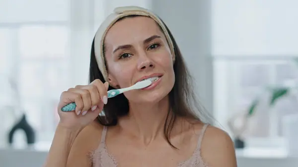 Happy lady dental hygiene routine at bathroom pov video. Brunette smiling woman brushing teeth at home close up. Cute girl clean mouth with toothpaste removing plaque portrait. Fresh smile concept