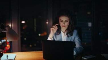 Yorgun bir ofis çalışanı gece geç saatlerde ofiste çalışıyor. Kapatın. Dizüstü bilgisayarda çalışan bunalmış iş kadını motivasyonsuz hissediyor. Profesyonel kız müdür gece bilgisayar ekranına bakıyor