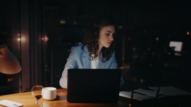 Gece geç saatlere kadar laptopta çalışan gülümseyen bayan. Bilgisayarda yazan belgelere bakan mutlu, güzel bir iş kadını. Neşeli ofis çalışanı kız e-postada iyi haberler veriyor. Başarı konsepti.