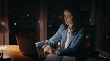 Kahve içen uykulu iş kadını ofis masasını gece geç saatte kapat. Genç yorgun kadın yönetici geceleri dizüstü bilgisayarda çalışıyor. Kendine güvenen girişimci kız iş sorunlarını kafein içeceğiyle çözüyor