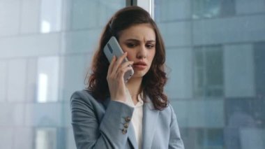 Sinirli iş kadını modern şirket işyerinden arıyor. Kapatın. Kafası karışmış bir kadın yönetici çalışma masasında iş belgelerine bakıyor ve gergin bir şekilde telefonla konuşuyor. Kızgın kız tatminsiz telefon konuşmaları.