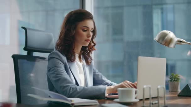女经理使用笔记本电脑与客户相对应 坐在豪华的办公室近旁 忙碌而严肃的女商人专心致志于计算机工作 在工作场所从事远程工作的有吸引力的女企业家 — 图库视频影像