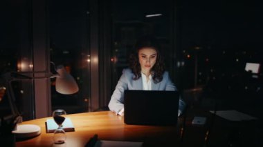 Aşırı yüklenmiş kadın ofis, yorgun gözleri kapatıp geceleri dizüstü bilgisayara bakıyor. Bilgisayar monitörünü izleyen mutsuz iş kadını şirket işyerinde bunalmış hissediyor. PC yazarken yorgun bayan yönetici.