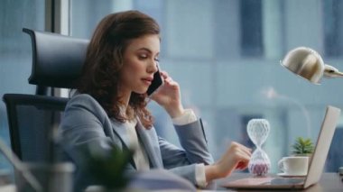 Çalışan meşgul bir kadın ofis masasını arıyor. Laptop monitörünü kapatıyor. Şirketin iş yerinde akıllı telefondan konuşan ciddi çekici bir iş kadını. Genç bayan patron telefonda iş hakkında konuşuyor..