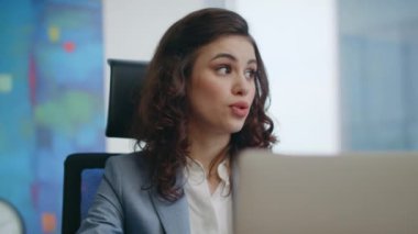 Bayan yönetici, iş yerindeki dizüstü bilgisayarlı kameralara danışmanlık yapıyor. Güzel bir iş kadını lüks ofisin video konferansını yönetiyor. Uzaktan kumandalı toplantıda kendinden emin çalışan kız konuşuyor..