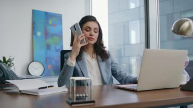 Başarılı bir iş kadını, iş yerinde dizüstü bilgisayarla telefonla konuşur. Akıllı telefonlara cevap veren zarif bir kadın şirket ofisinde oturuyor. Kendine güvenen bir kız iş görüşmesi yapıyor..