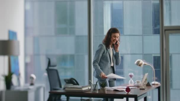 Женщина Менеджер Говорит Смартфоне Стоящем Возле Рабочего Стола Счастливая Улыбающаяся — стоковое видео