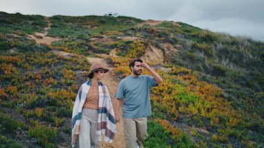 Romantik çift tepenin aşağısında bulutlu güzel bir manzaraya bakıyor. Rahatlamış, çekici bir çift, çim yamaçta el ele tutuşarak yürüyor. İki insanı sevmek doğada dinlenmek ve birlikte gezinin tadını çıkarmak..